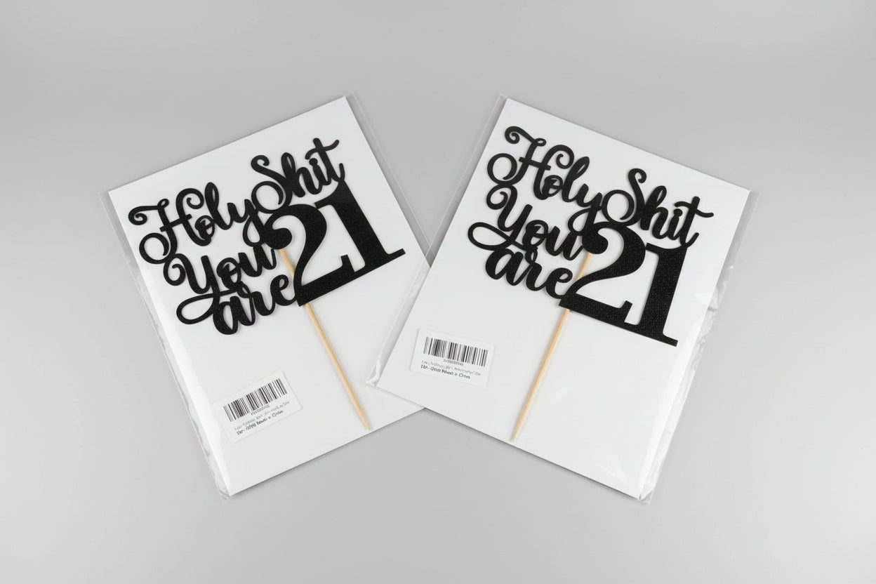 Two 'Holy Shit You Are 21' cake toppers on packaging with a neutral background.