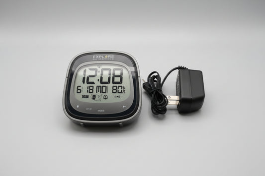 Digital clock with power adapter on a beige surface